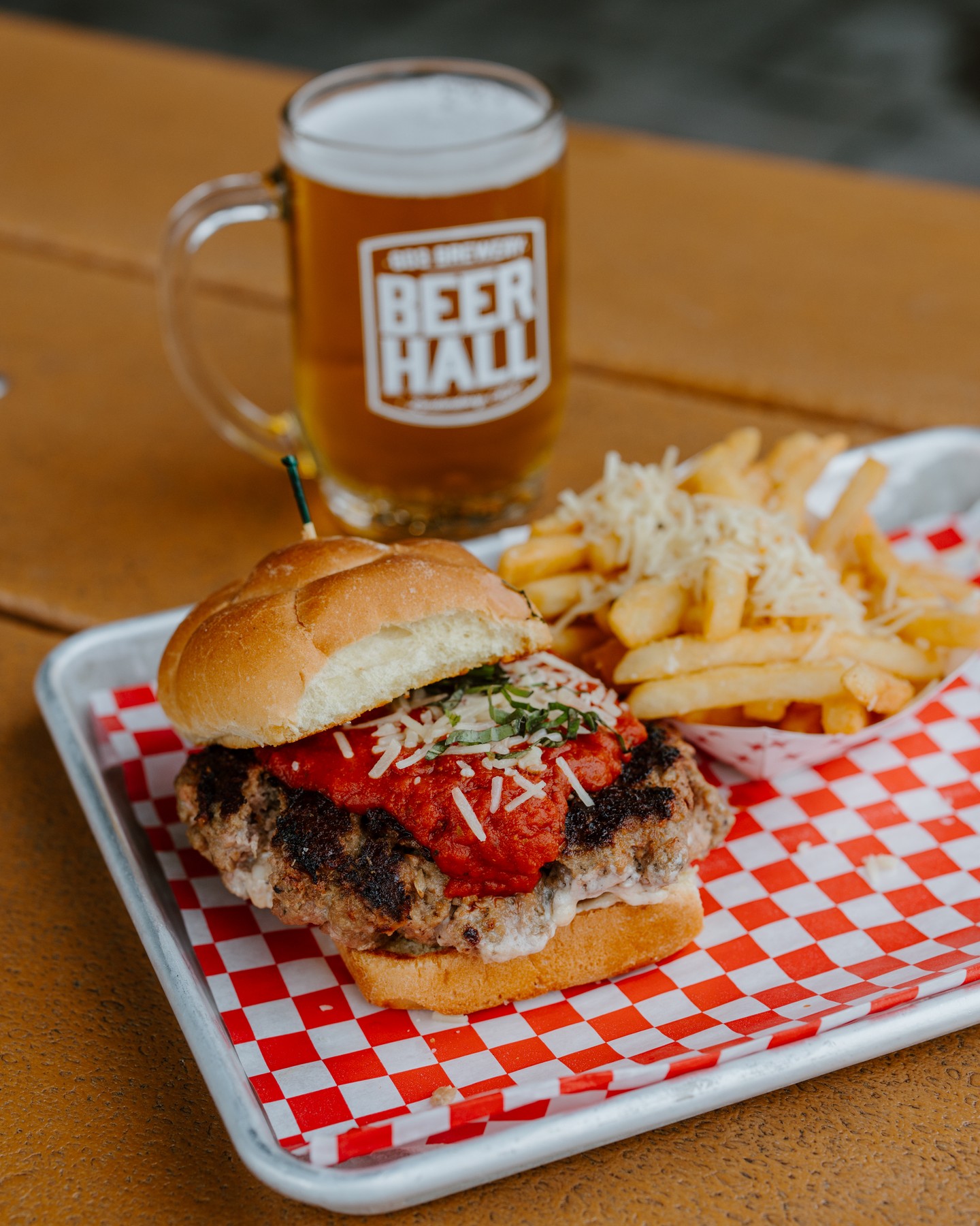 Join us today for a hearty "meatball stuffed burger" to be paired with a crisp and refreshing Beer Hall Lager. The Stuffed Meatball Burger perfectly pairs with our crisp and refreshing Beer Hall Lager. The savory combination of house-made meatballs, smoked mozzarella, pepperoni, and tomato fondue brings plenty of rich, bold flavor, while BHL's clean, crisp finish helps keep each bite fresh and pleasant. It's subtle bread-y sweetness complements the bulky roll and savory meatball, while the mild fruity and herbal hop notes add just enough contrast against the smoky mozzarella and tomato. Paired with Parmesan garlic fries, it’s a classic combination of rich, savory comfort food and crisp, refreshing beer-flavored-beer! You won't want to miss this one!