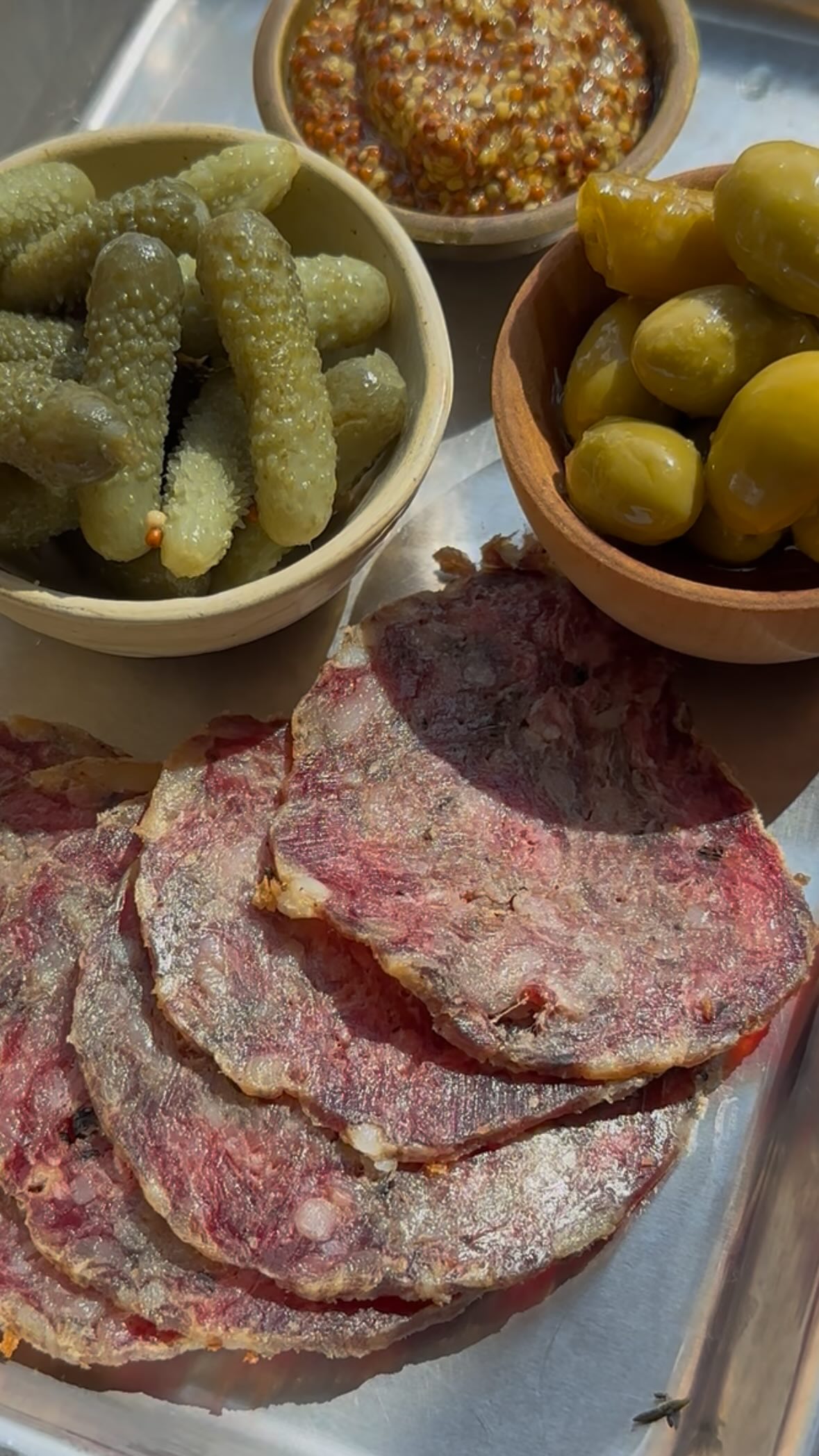HOMEMADE SALAMI
Who knew making charcuterie at home was so easy? My friend Uri Meir Chizik (@mayerchissick), Israel’s preeminent food historian and one of its top fermentation experts, came over to show me how. What I learned was that the main ingredients are ground meat, salt, and patience. If you have an extra fridge, this will be easier for you, but even if you don’t, a small wire rack set atop a sheet plan or plate works like a charm. You just need a month to wait, then slice as thinly as possible. Definitely worth trying at home!
2 lbs 2 oz (1 kg) 80/20 ground beef
1 oz/ (30 g) Diamond kosher salt (or 2 1/4 TB Morton’s or Israeli coarse salt)
1 teaspoon freshly ground black pepper
Optional additions:
1/4 cup (60 ml) olive oil
1/2 teaspoon ground sumac
1 tablespoon fermented hot sauce
1 teaspoon ground coriander seed
1 teaspoon turmeric
In a bowl combine the meat, salt, and pepper by hand, kneading until the mixture is uniform. Transfer to an airtight container and refrigerate for 24 hours. Use clean hands to shape the mixture into a salami using parchment paper, twisting at the edges to tighten into a tube. Arrange the salami on a wore rack over a small baking sheet or plate. Let sit, uncovered, until the salami has darkened in color and hardened, at least 1 month. For a drier salami, let it continue to dry in the fridge for another 1-2 months, turning every few days.