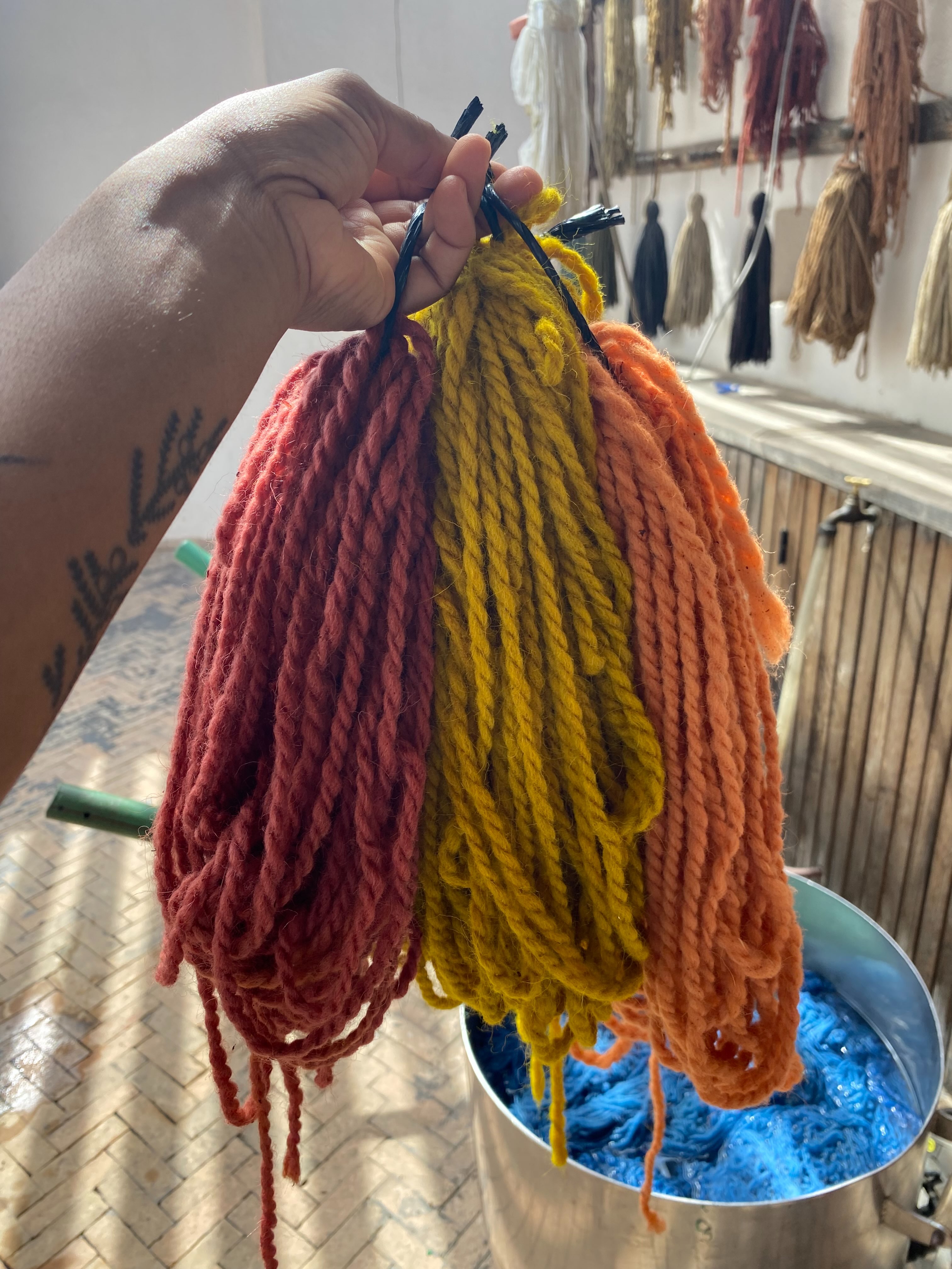 I had a great day at @the.anou attending a natural dyeing workshop, which turned out to be a private lesson because no one else was signed up. We walked to the local market to source the dyestuff, ground up the materials in a mortar and pestle and then we got two dye vats going with two different colors. The first dark red one is madder root, the brighter, orange pink one is madder root with alum, and the greenish yellow one is hibiscus, turmeric, and alum. They also have residencies which I wish I had known about because I definitely would have done it! Maybe in another life 🧶 the yarn is from @atlaswoolsupplyco based in the Atlas Mountains in Morocco, Africa’s first carbon negative yarn