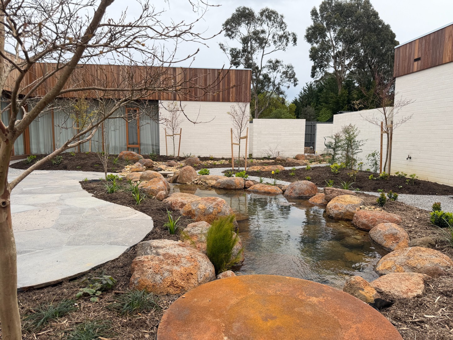 A project we have had the pleasure of supplying from the ground up. Every material across this Macedon Ranges courtyard came through Macedon Nursery & Garden Supplies, from the bark mulch and garden soil through to the crushed granite pathways, bluestone paving, granite boulders edging the pond, and the upright granite monoliths placed as feature stones throughout the space.
The advanced deciduous trees are just breaking into their first spring, which gives a sense of how this space will read once the plantings fill out over the coming seasons.
A project like this demonstrates what's possible when the landscape designer and the supplier are both working from the same list.
#macedonnursery #macedonrangesgardens #landscapesupplies